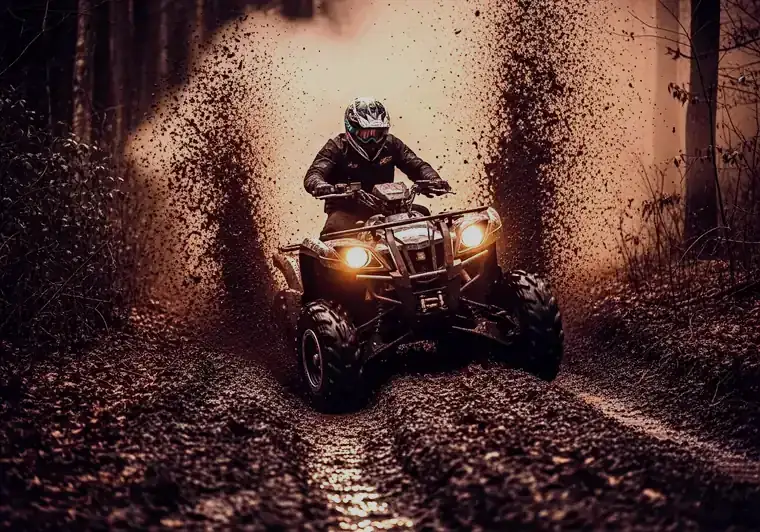 ATV powering through deep mud on a wooded trail