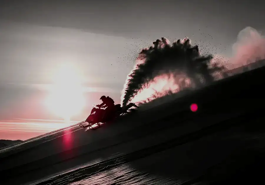 Snowmobile throwing powder on a mountain slope