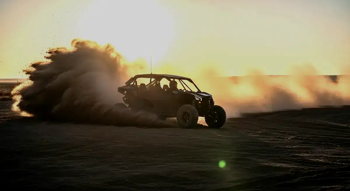 Side-by-side UTV throwing a dust plume at dusk